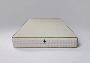 Front view of a high-end mattress with a white quilted side and brown trim, showcasing the Dominique Bienfait logo and emblem at the center.