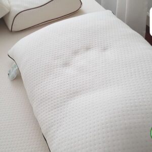 Close-up of a white pillow with a textured cover, showcasing its "Natural Living Concept" and "100% Naturel Latex" labels.
