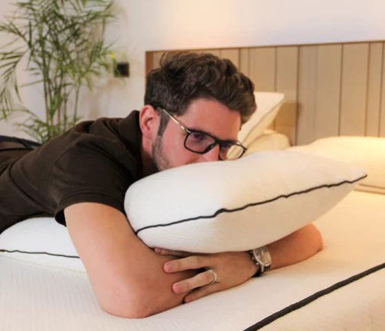 Un homme est allongé sur le ventre sur un lit, la tête posée sur un oreiller moelleux en latex.