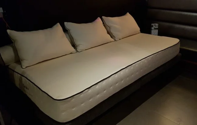 Un matelas en latex blanc d'apparence confortable avec trois oreillers sur le dessus, reposant sur un cadre de lit plateforme.