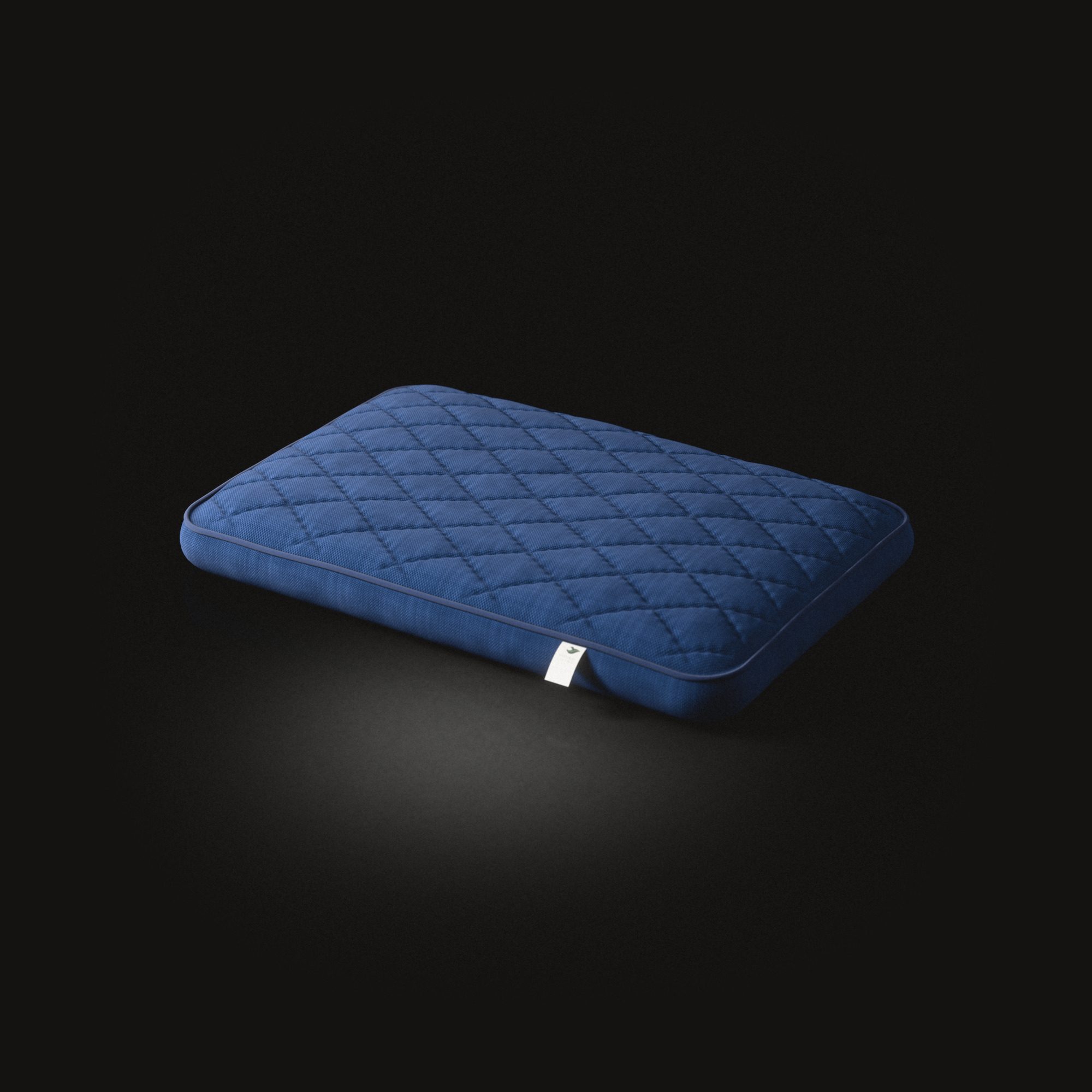 The rectangular dog cushion on a black floor, its top quilted in diamonds.