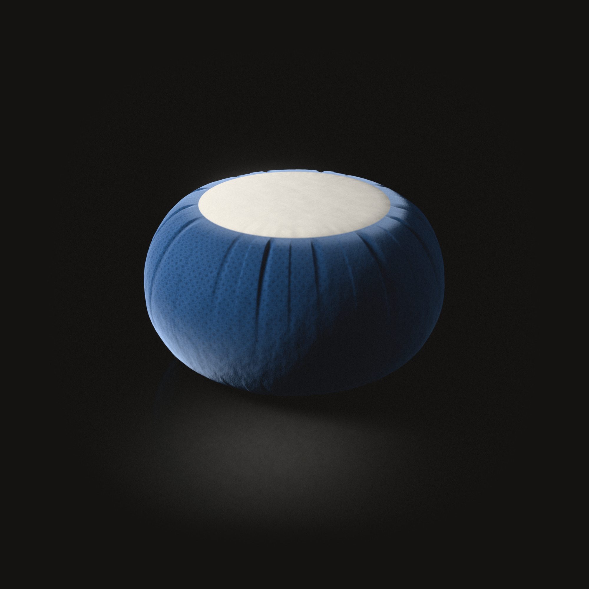 The zafu on a black floor: a round cushion with a pleated side and a flat circle of cotton on top.