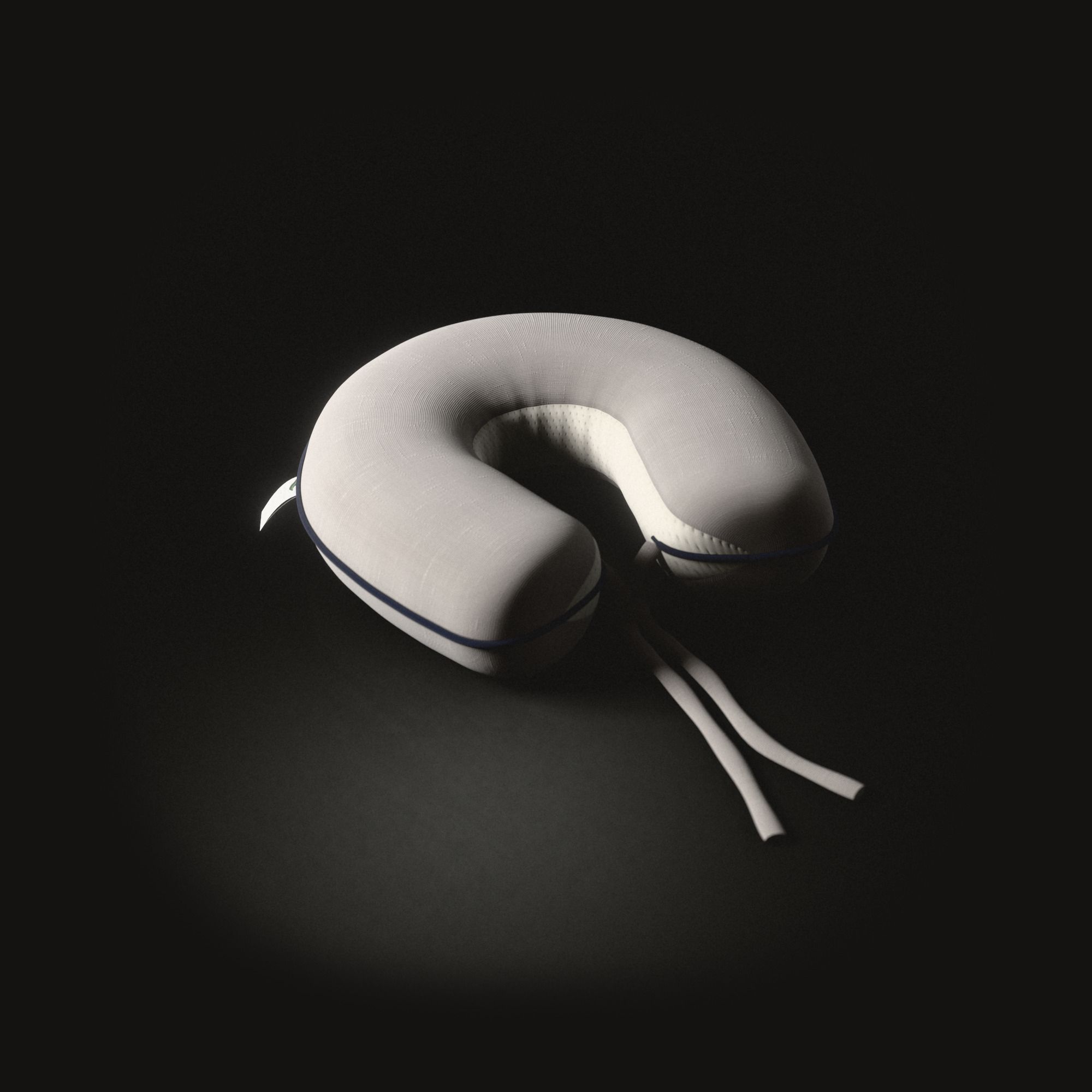 A greige neck pillow shaped like a horseshoe on a black floor, a band of cream knit inside its bend, a navy cord along its outer edge, two cloth ties knotted between its ends.