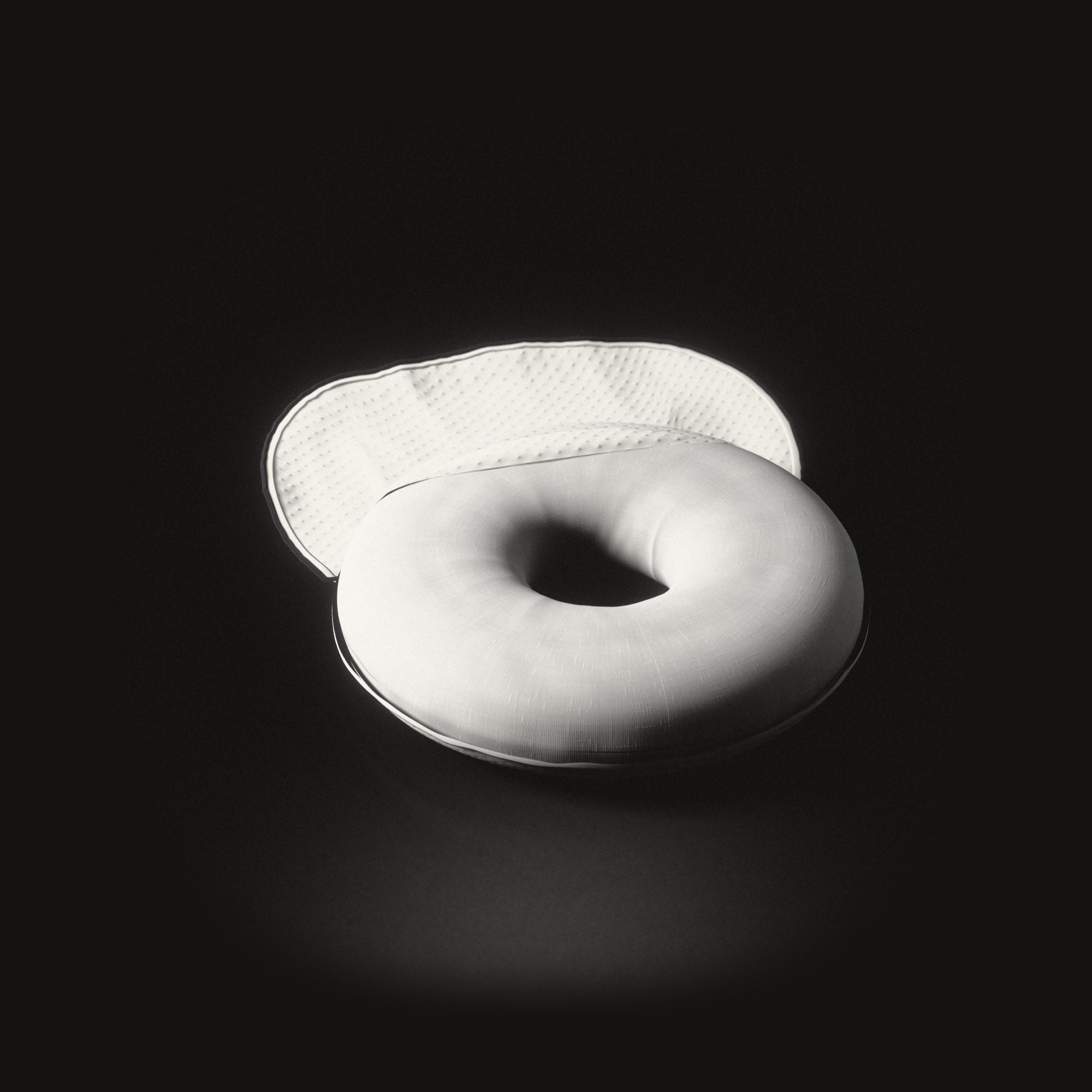 The ring cushion on a black floor, its knitted cover unzipped and turned back behind it.
