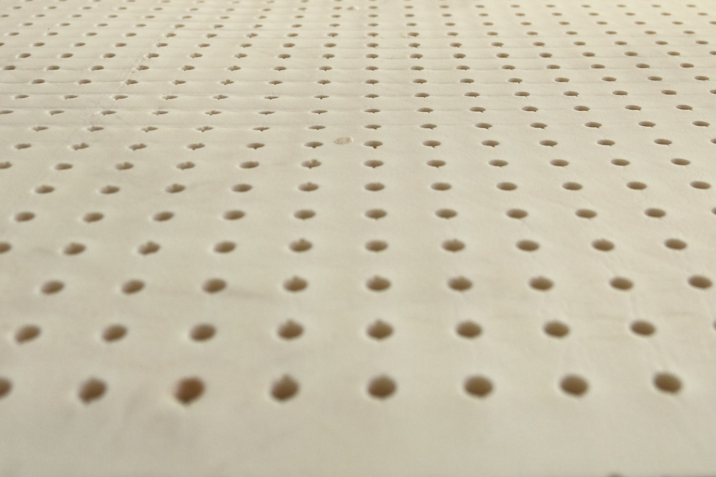 Pin holes running across a layer of natural latex, seen from low down.