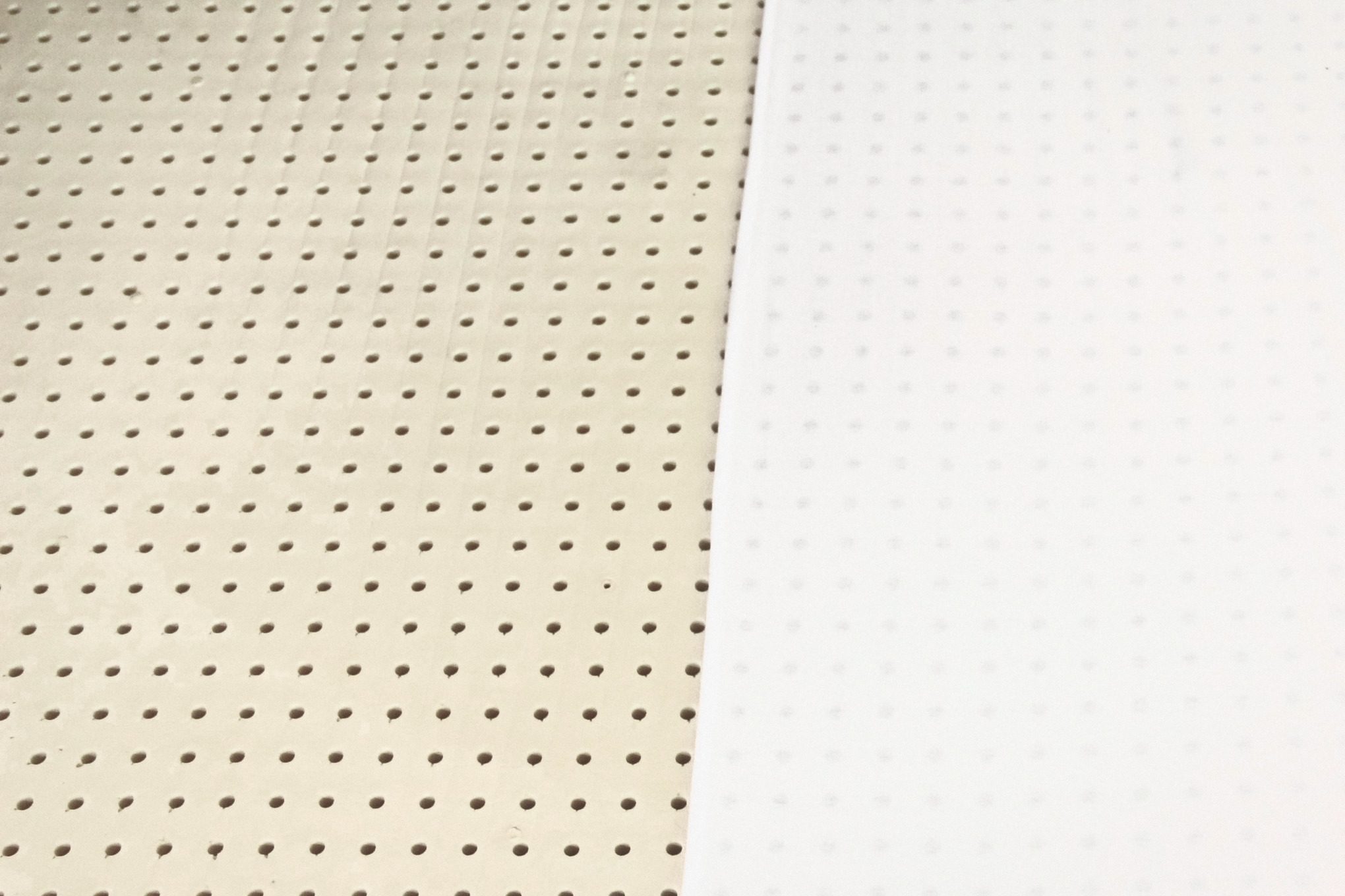 A sheet of cream latex with rows of pin holes, and beside it the same latex under a thin white cloth through which the holes show.