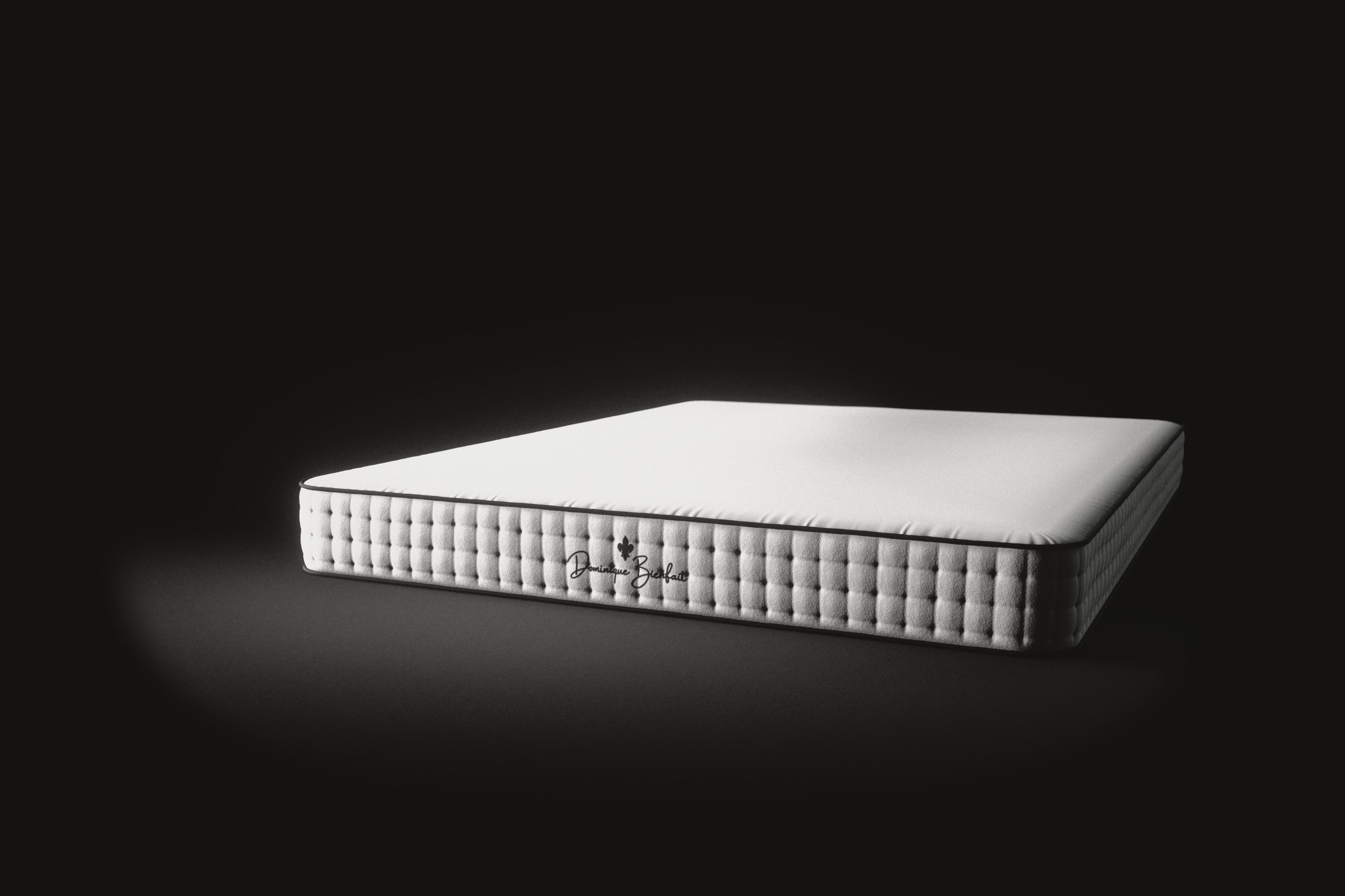 A white mattress on a black floor, seen three quarters from its foot end: a tufted side with a black fleur-de-lis and the name Dominique Bienfait, black piping, and a smooth white top.