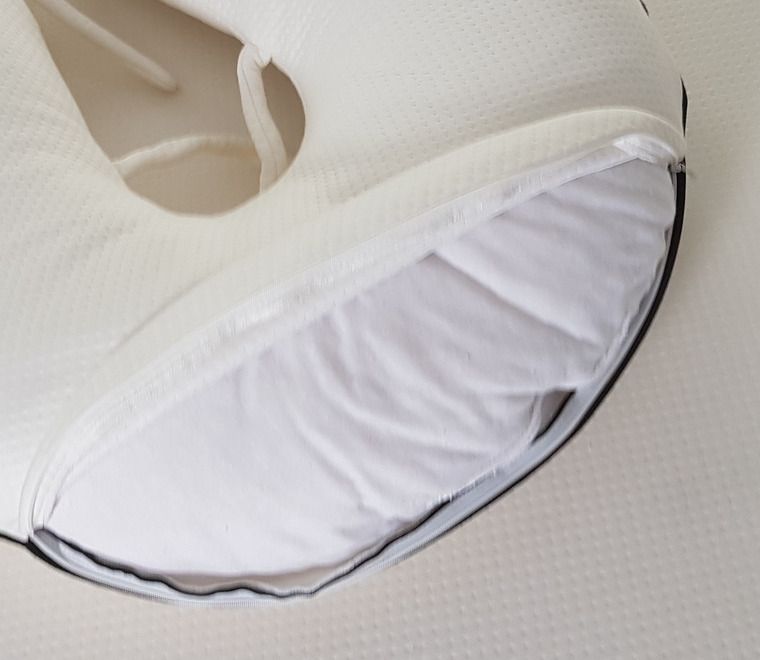 The nursing cushion seen close with its cover unzipped, the white inner cushion showing.